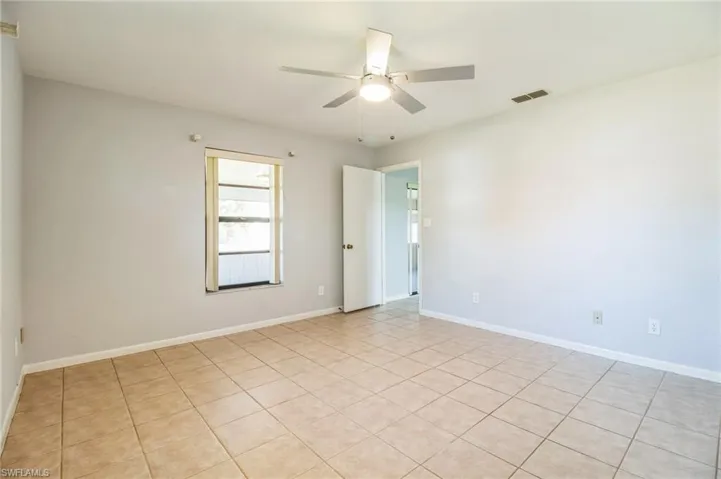 Tiled spare room featuring ceiling fan