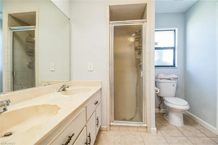 Bathroom featuring toilet, tile patterned flooring, vanity, and walk in shower