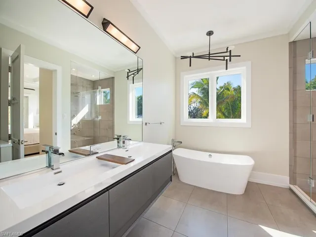 Bathroom with a freestanding bath, vanity, a stall shower, and light tile patterned floors