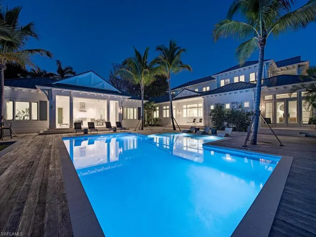 Pool at night featuring an outdoor pool, a patio, an exterior structure, and an outbuilding