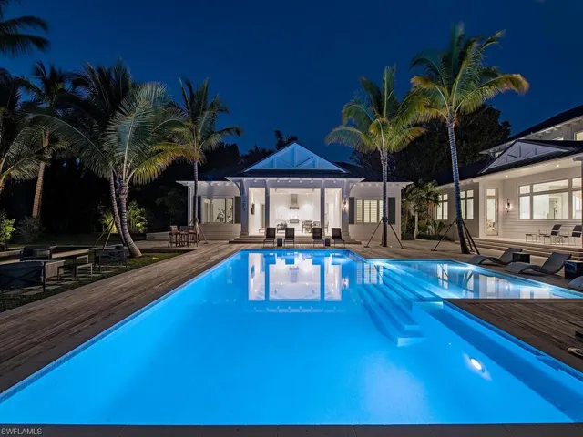 Pool at night with a storage structure, an outbuilding, a patio area, an outdoor hangout area, and a pool with connected hot tub