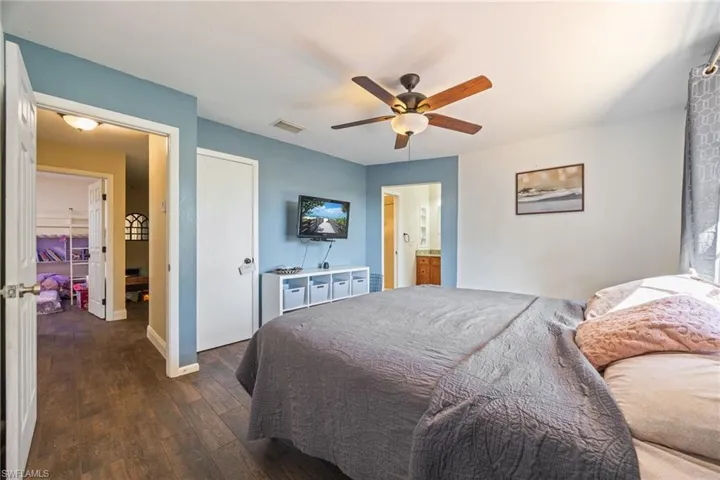 Bedroom featuring dark wood-style floors, ceiling fan, and ensuite bathroom