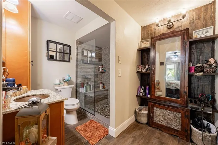 Full bathroom with vanity, dark wood-style flooring, connected bathroom, and a stall shower