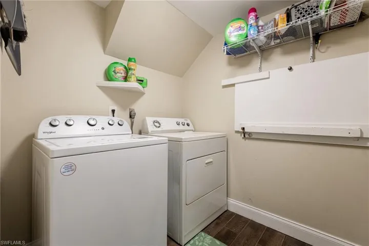 Laundry area with wood tiled floors, washing machine and dryer, and vaulted ceiling