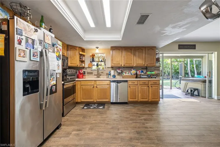 Kitchen with appliances with stainless steel finishes, tasteful backsplash, light countertops, and dark wood-style flooring