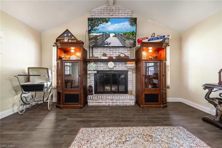 Sitting room with vaulted ceiling, a fireplace, and dark wood-style floors