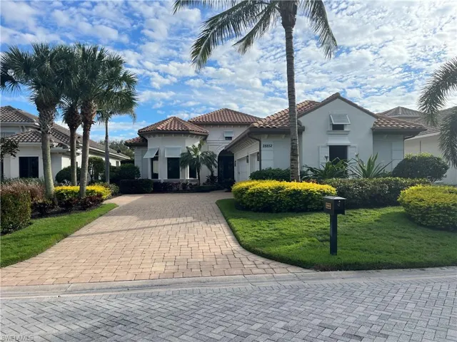 Mediterranean / spanish-style home featuring decorative driveway, stucco siding, a front yard, a garage, and a tiled roof