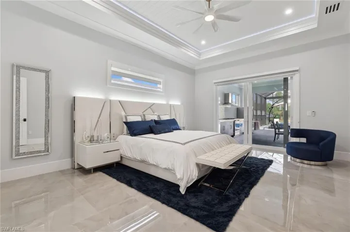 Bedroom with a tray ceiling, baseboards, crown molding, and access to outside
