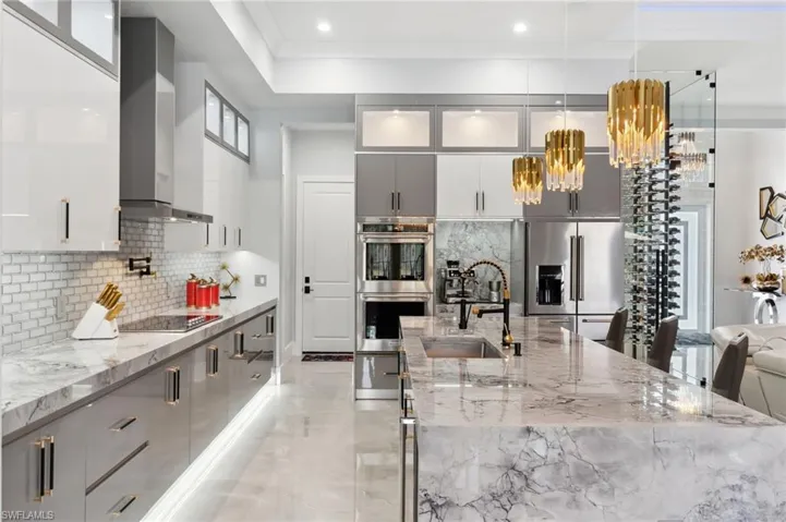 Kitchen featuring gray cabinetry, a sink, appliances with stainless steel finishes, wall chimney exhaust hood, and modern cabinets