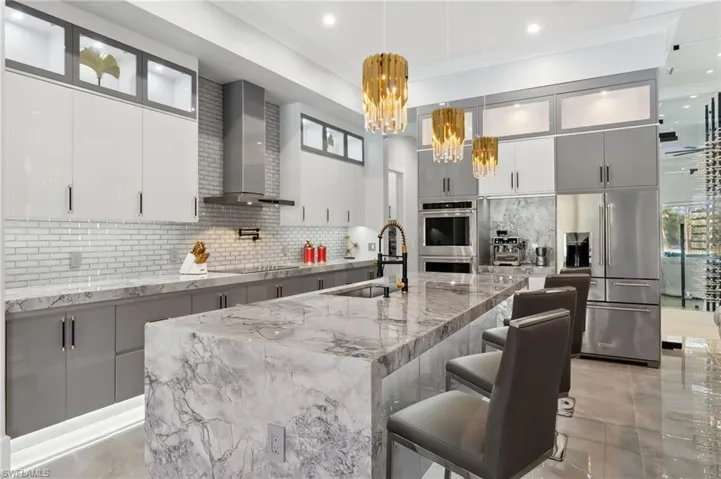 Kitchen featuring a sink, modern cabinets, appliances with stainless steel finishes, and wall chimney range hood