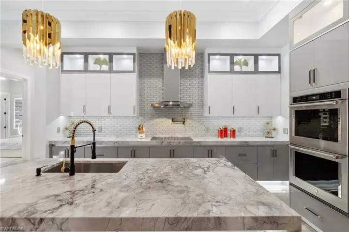 Kitchen with a sink, decorative backsplash, stainless steel double oven, and a chandelier
