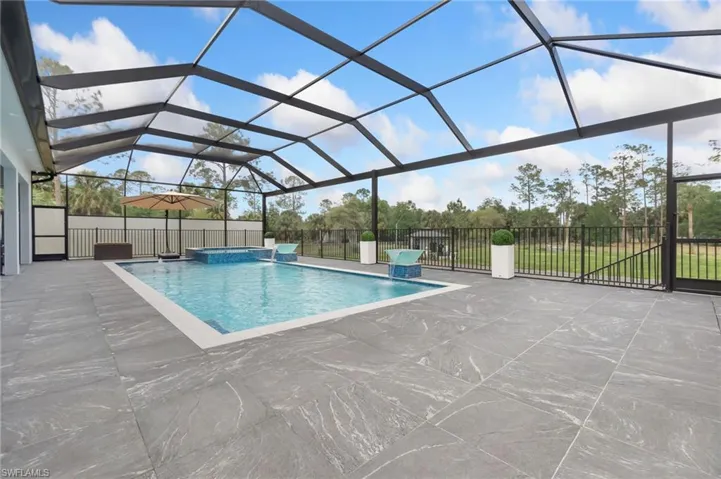 View of pool with a patio, fence, a lanai, and a pool with connected hot tub
