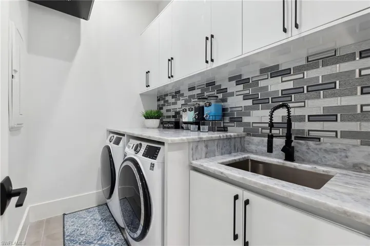 Washroom with baseboards, cabinet space, a sink, tile patterned floors, and independent washer and dryer