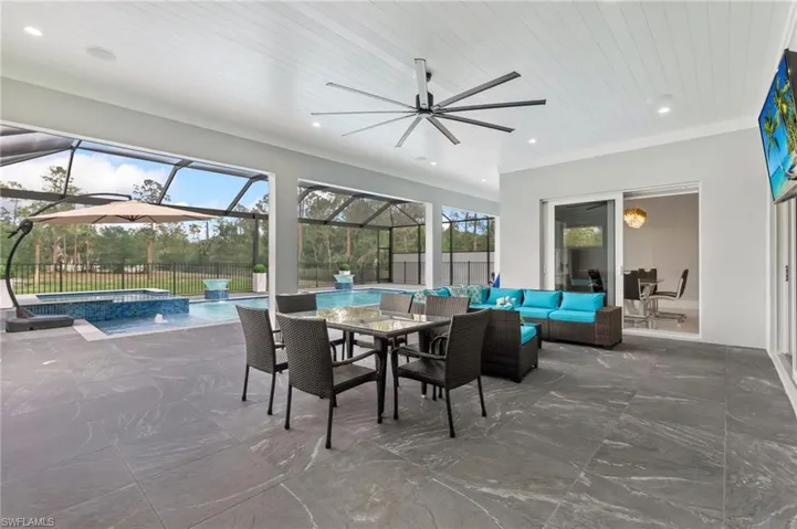 View of patio / terrace featuring glass enclosure, a ceiling fan, fence, an outdoor living space, and outdoor dining area