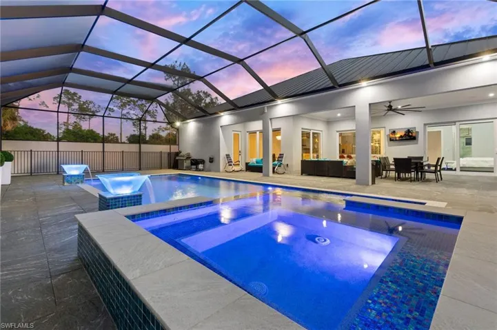 Pool at dusk featuring a patio, a fenced in pool, an in ground hot tub, ceiling fan, and outdoor lounge area