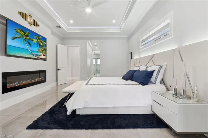 Bedroom with baseboards, visible vents, a tray ceiling, recessed lighting, and ornamental molding