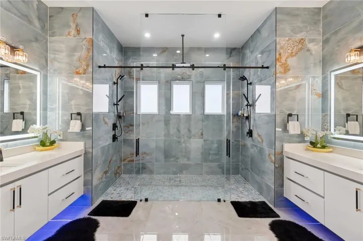 Full bathroom with a shower stall, two vanities, and tile walls