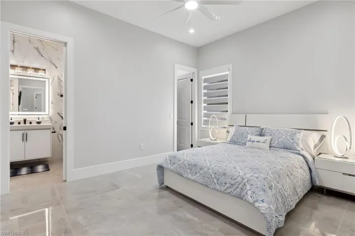 Bedroom featuring ceiling fan, ensuite bathroom, and baseboards