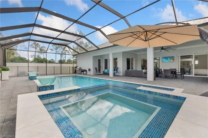 View of pool with an outdoor living space, a pool with connected hot tub, glass enclosure, a patio, and a ceiling fan