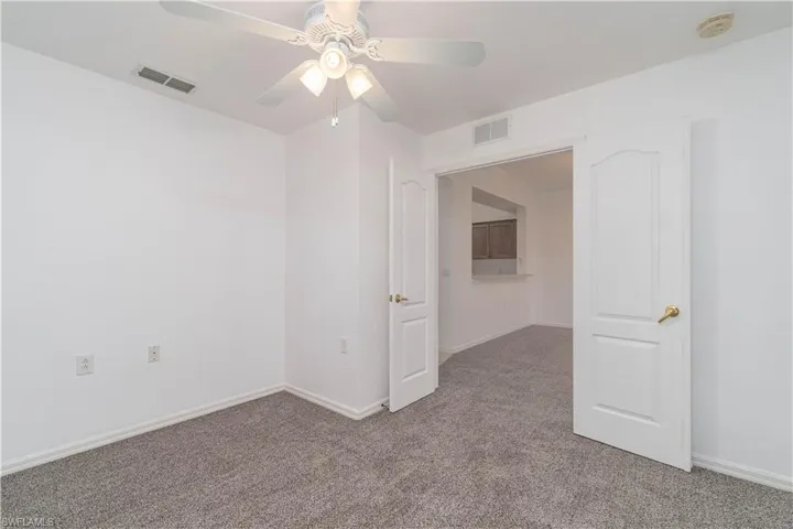 Unfurnished room featuring baseboards, visible vents, a ceiling fan, and light colored carpet