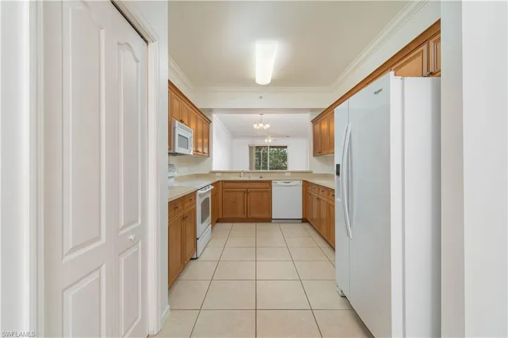 Kitchen featuring light countertops, ornamental molding, a sink, white appliances, and a chandelier