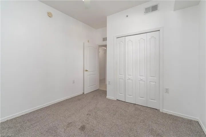Unfurnished bedroom featuring a closet, carpet floors, visible vents, and baseboards