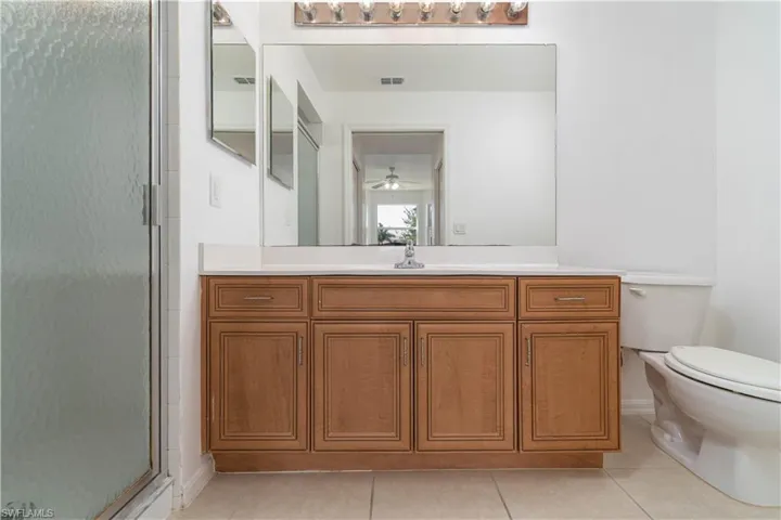 Full bath featuring a shower stall, visible vents, tile patterned floors, and toilet