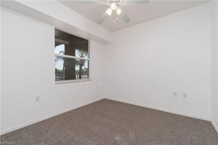 Carpeted empty room featuring a ceiling fan and baseboards