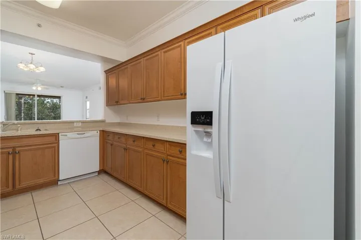 Kitchen featuring brown cabinetry, white appliances, and ornamental molding