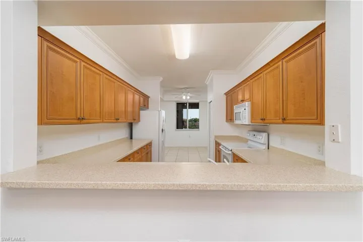 Kitchen with light countertops, a ceiling fan, white appliances, and a peninsula