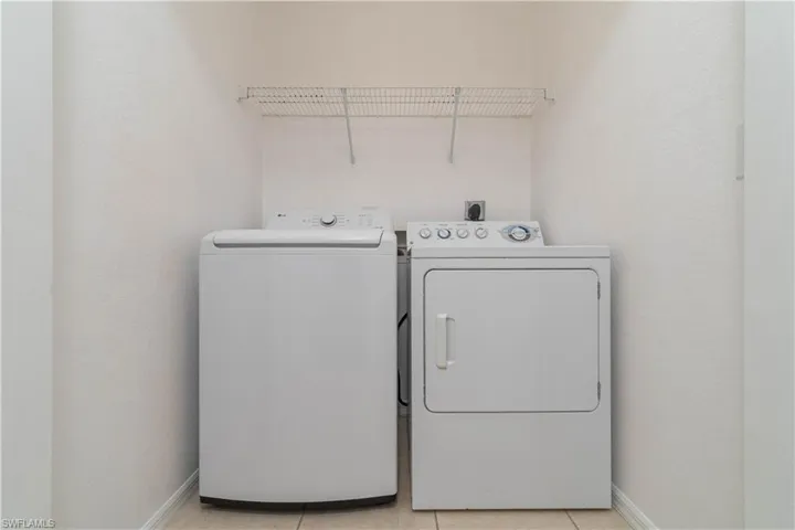 Washroom featuring washing machine and dryer, baseboards, laundry area, and light tile patterned flooring
