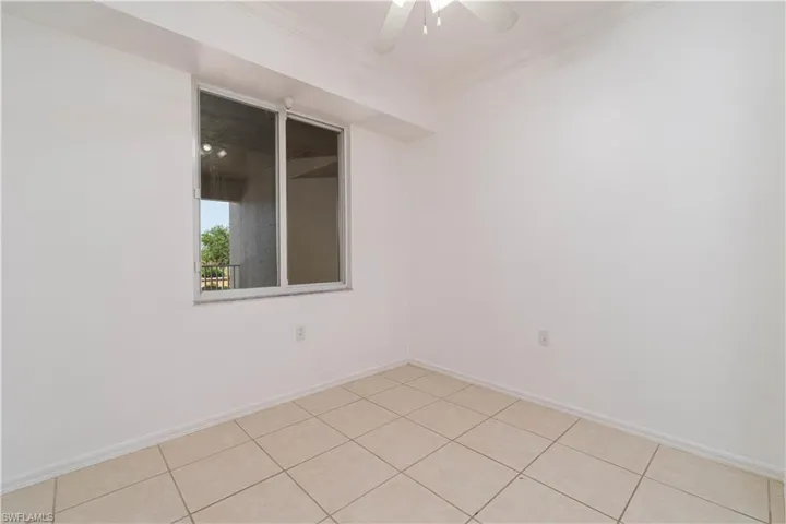 Empty room featuring baseboards, light tile patterned flooring, ceiling fan, and crown molding