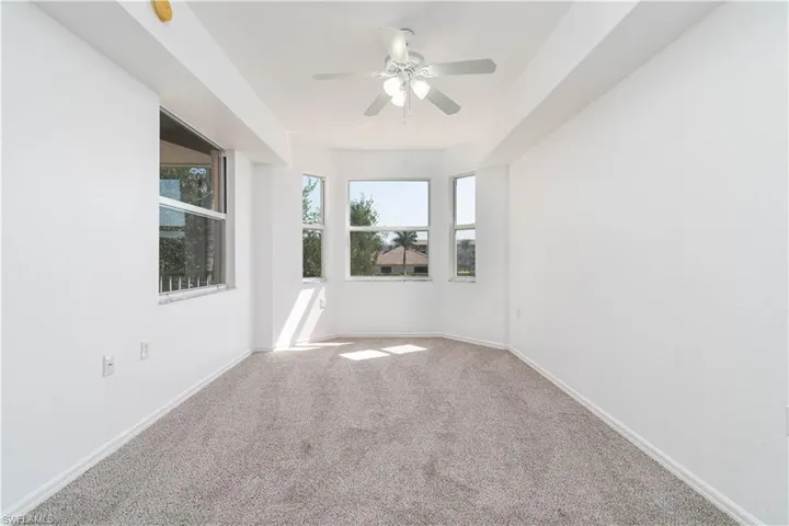 Carpeted empty room featuring baseboards and a ceiling fan