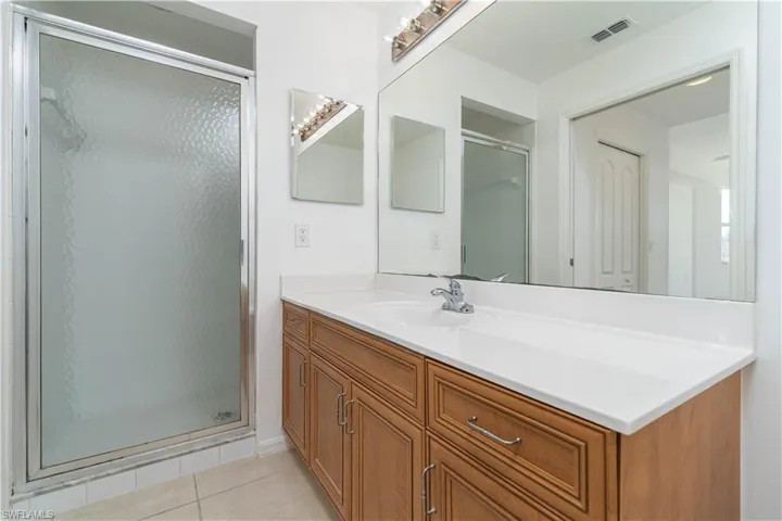 Bathroom with a shower stall, vanity, tile patterned floors, and visible vents