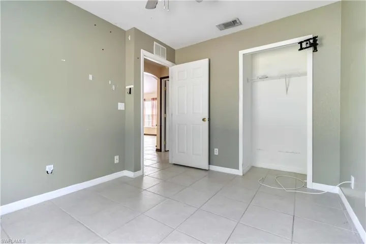 Unfurnished bedroom with light tile patterned floors, a closet, and a ceiling fan