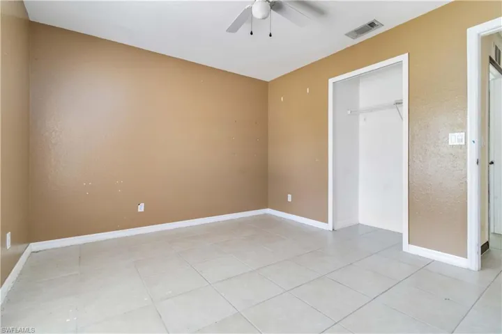 Unfurnished bedroom with light tile patterned floors, ceiling fan, and a closet