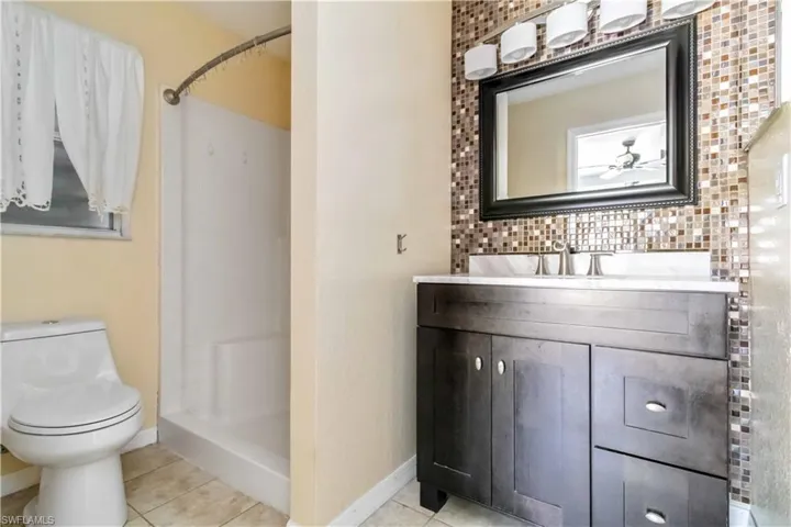 Bathroom featuring vanity, light tile patterned floors, a shower stall, and tasteful backsplash