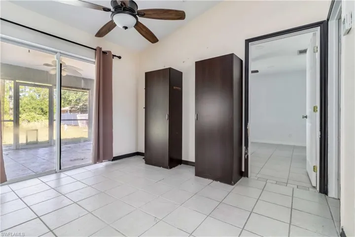 Unfurnished bedroom with light tile patterned floors, access to exterior, and ceiling fan