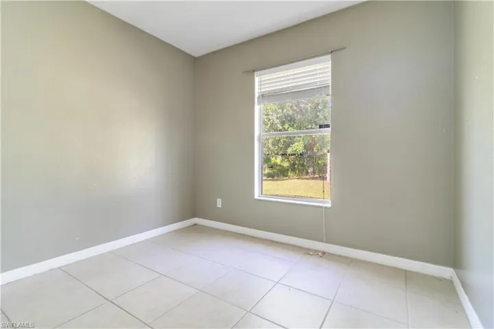 Empty room featuring baseboards and light tile patterned floors