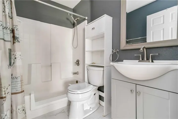 Full bathroom with vanity, marble look tiles, and shower / tub combo