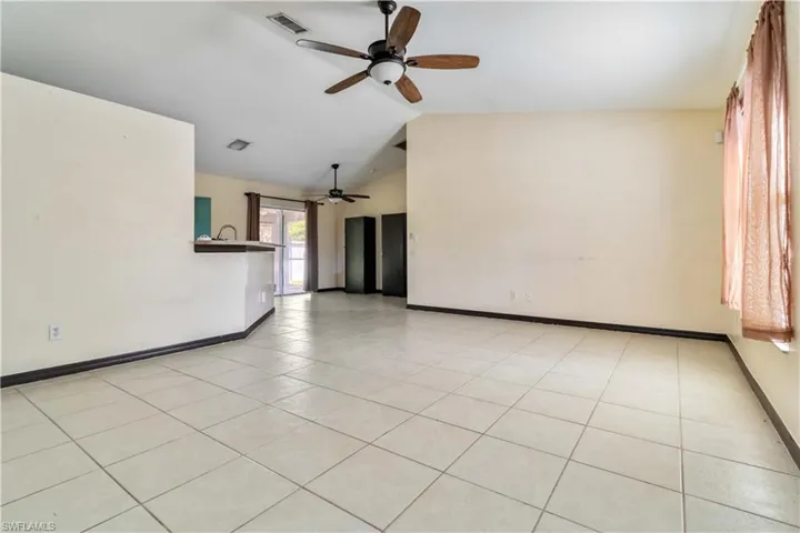 Spare room with lofted ceiling, light tile patterned floors, and ceiling fan