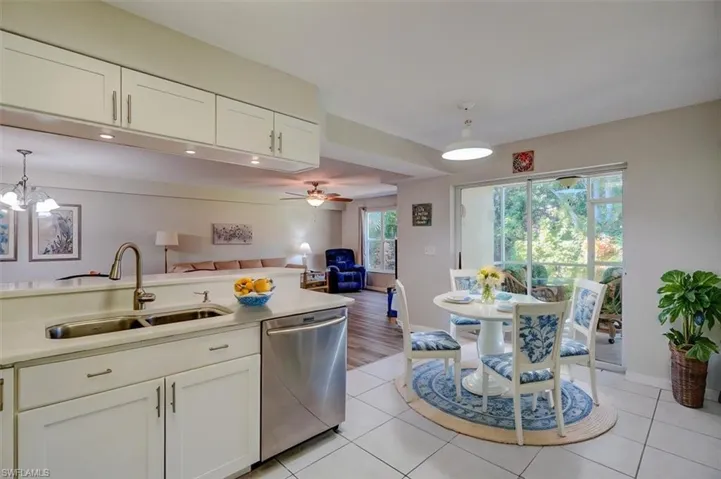 Kitchen featuring pendant lighting, white cabinetry, stainless steel dishwasher, light tile patterned floors, and open floor plan