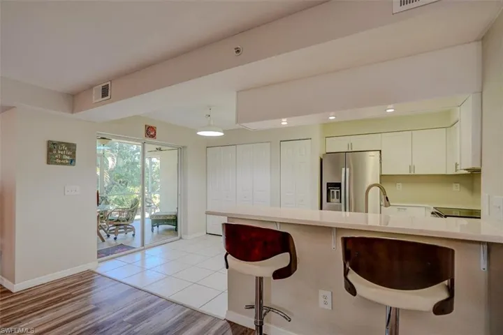Kitchen featuring a breakfast bar area, a peninsula, stainless steel fridge, light wood-style flooring, and white cabinets