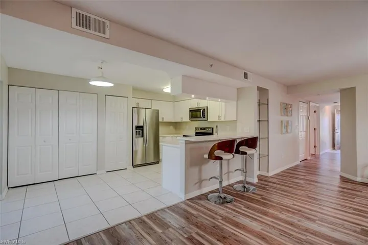 Kitchen with light countertops, stainless steel appliances, a breakfast bar, light wood finished floors, and a peninsula