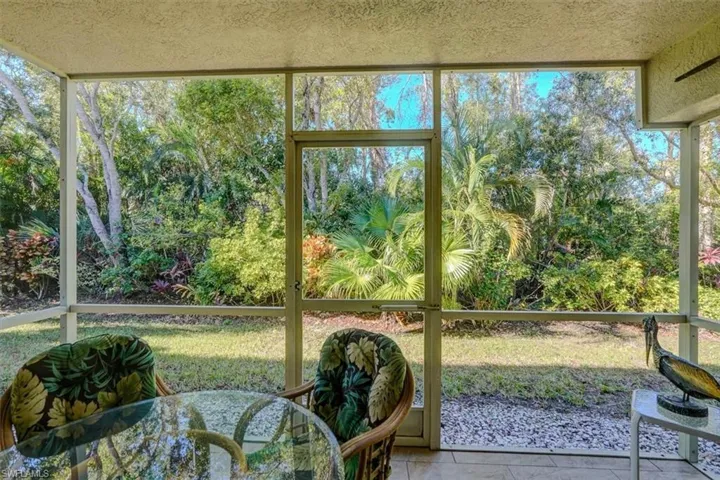 Sunroom / solarium with view of wooded area and healthy amount of natural light