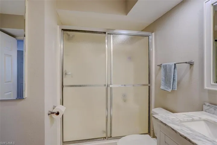 Bathroom with vanity, a textured wall, and a shower stall