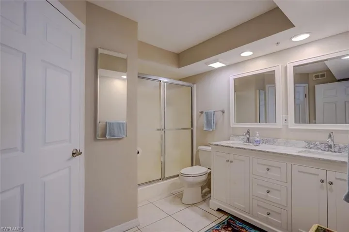 Full bath featuring light tile patterned flooring, double vanity, recessed lighting, and shower / bath combination with glass door
