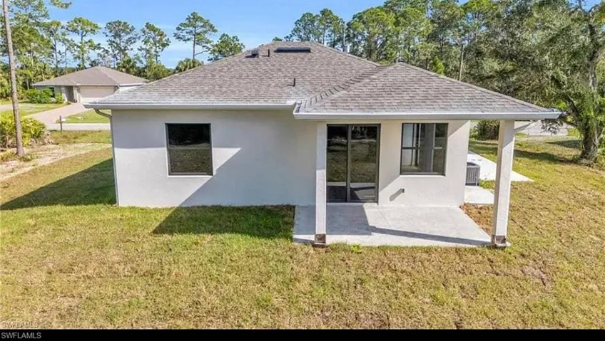 Back of property with stucco siding, a yard, a shingled roof, and a patio area