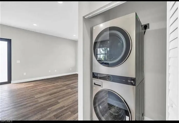 Laundry area featuring stacked washing machine and dryer, dark wood-style floors, and recessed lighting