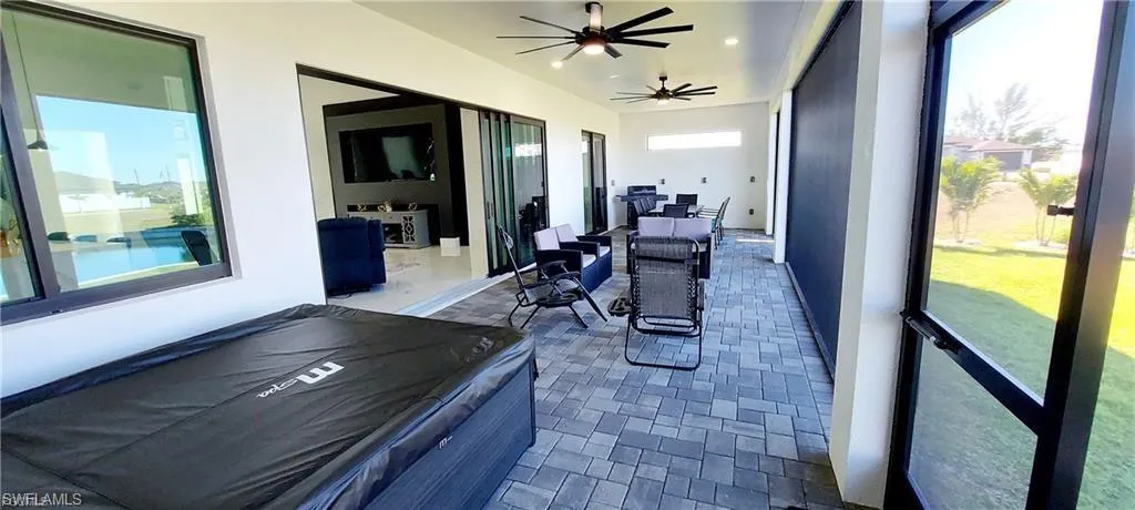 Expansive outdoor living area featuring a covered patio with ceiling fans, paver flooring, and retractable screens